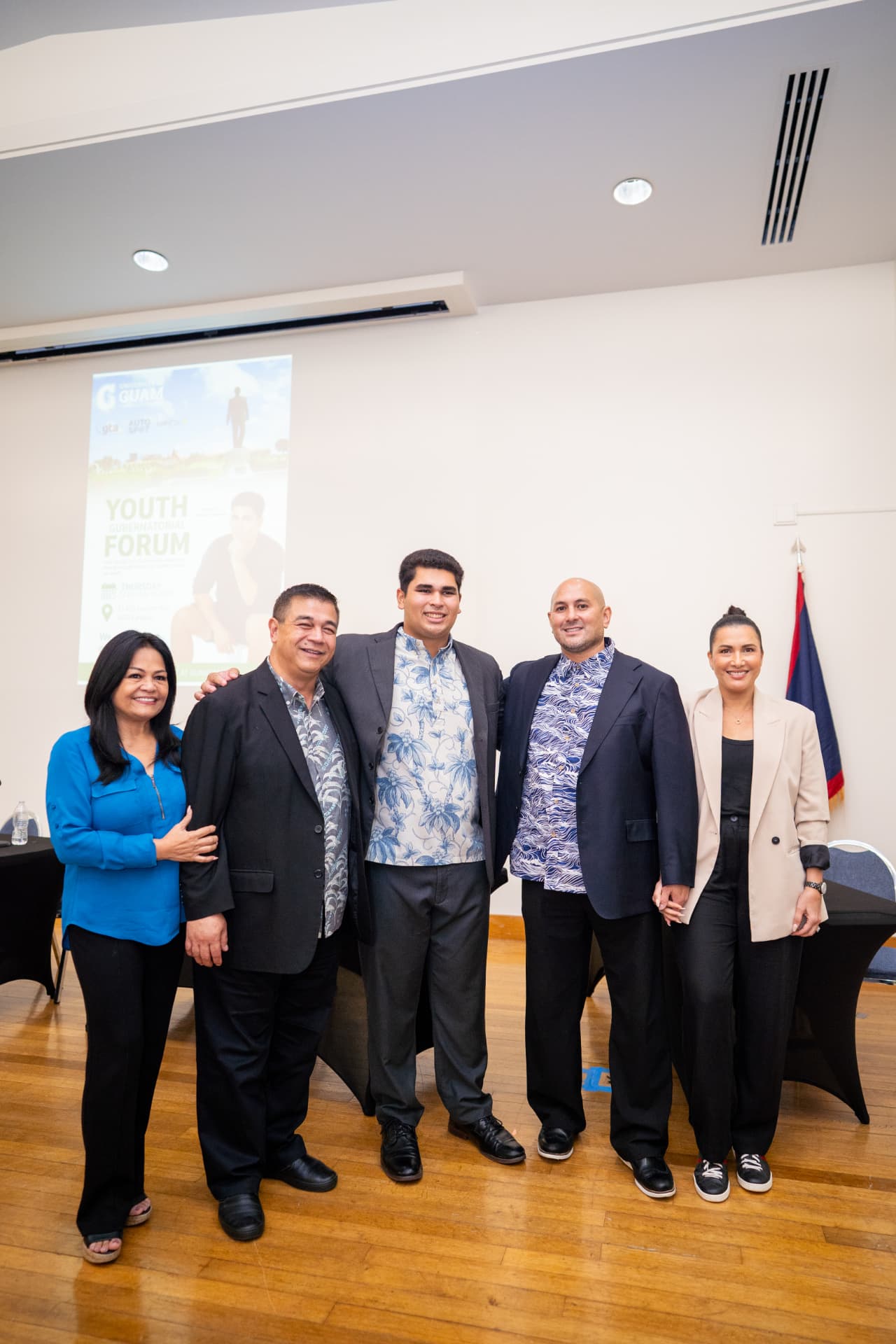 Genesis Babauta with gubernatorial candidates in front of the Youth Gubernatorial Forum banner
