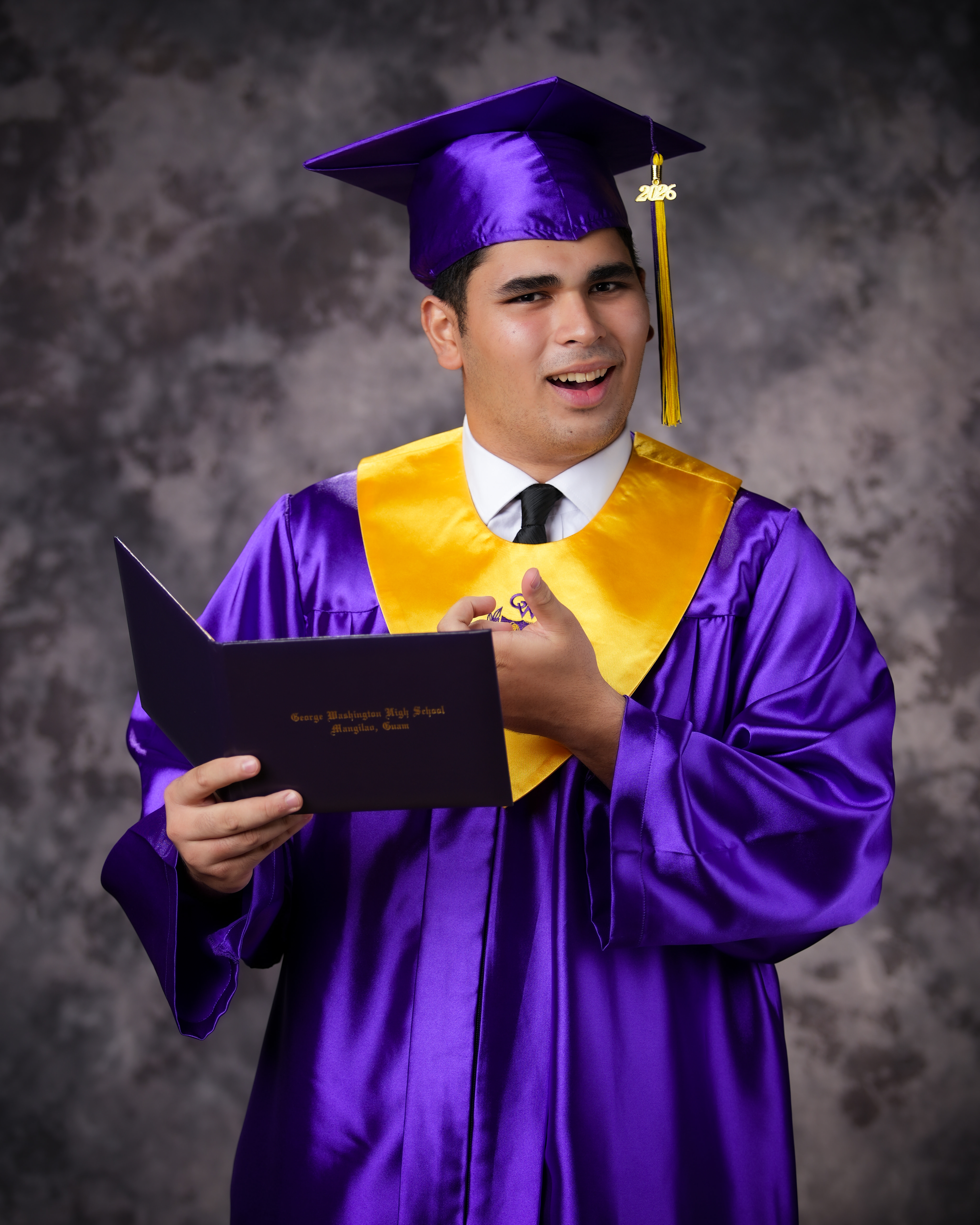 Genesis Babauta smiling in cap and gown at graduation